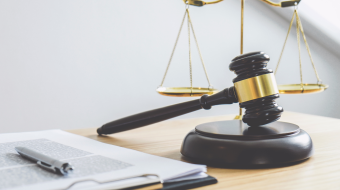 A judge's gavel and scales of justice on a desk.