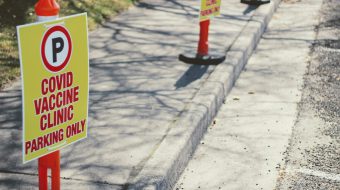 Signs along a street indicating parking for covid vaccine clinic only.