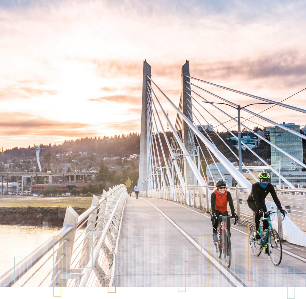 Man and woman biking across a bridge in the Pacific Northwest.