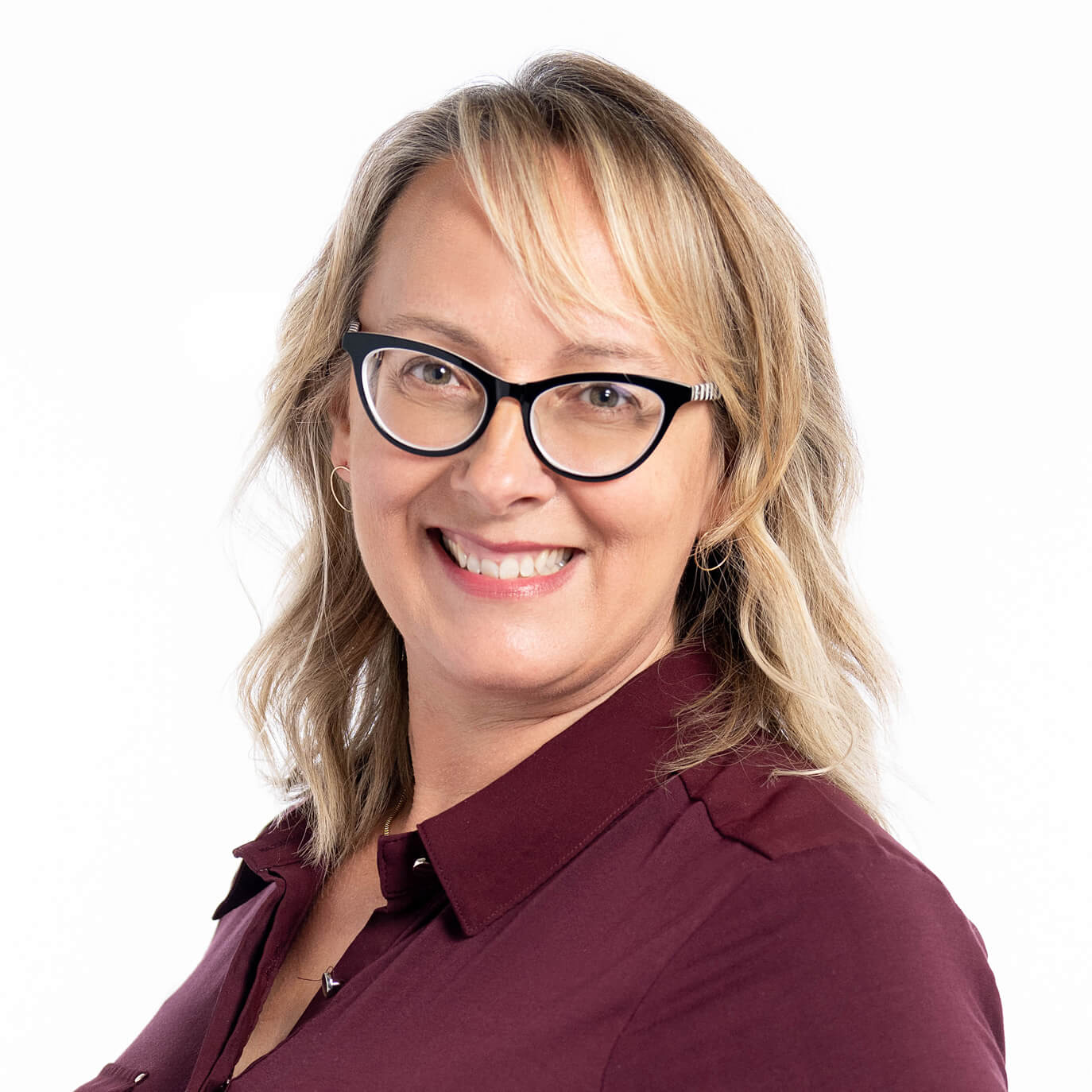 Blonde woman in maroon top and black horn-rim glasses smiling.