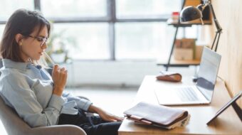 Photo of woman wearing glasses and looking down at desk