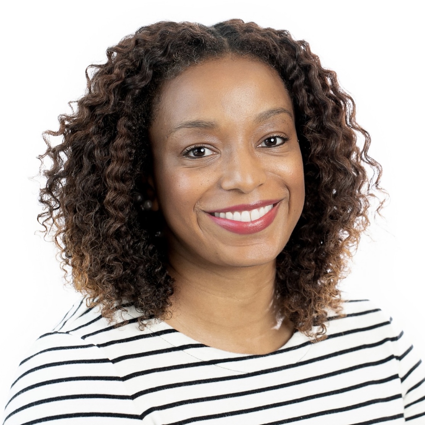 Tanisha Tate Woodson, with dark curly hair and brown eyes, smiling, and wearing a white blouse with black stripes.